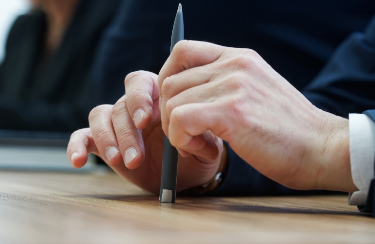 man holds a fountain pen while sitting at a table