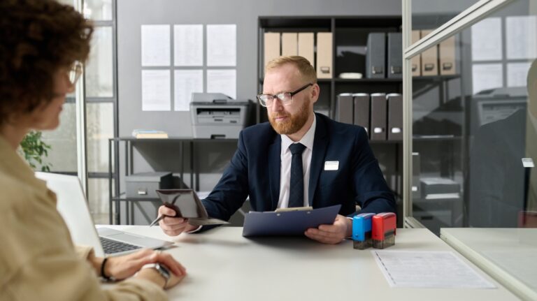 Portrait of bearded worker checking passport of young woman in immigration